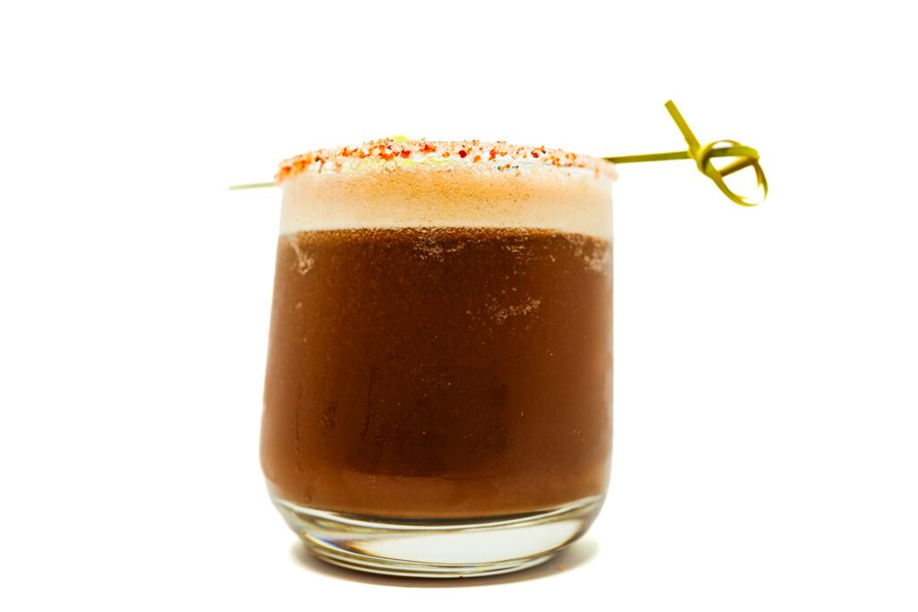 Orange Mocha Mezcal Margarita served in a glass, rimmed with Tajín and garnished with a lime wedge, featuring a bold combination of smoky mezcal, rich mocha, and fresh orange flavors for a unique and flavorful cocktail.