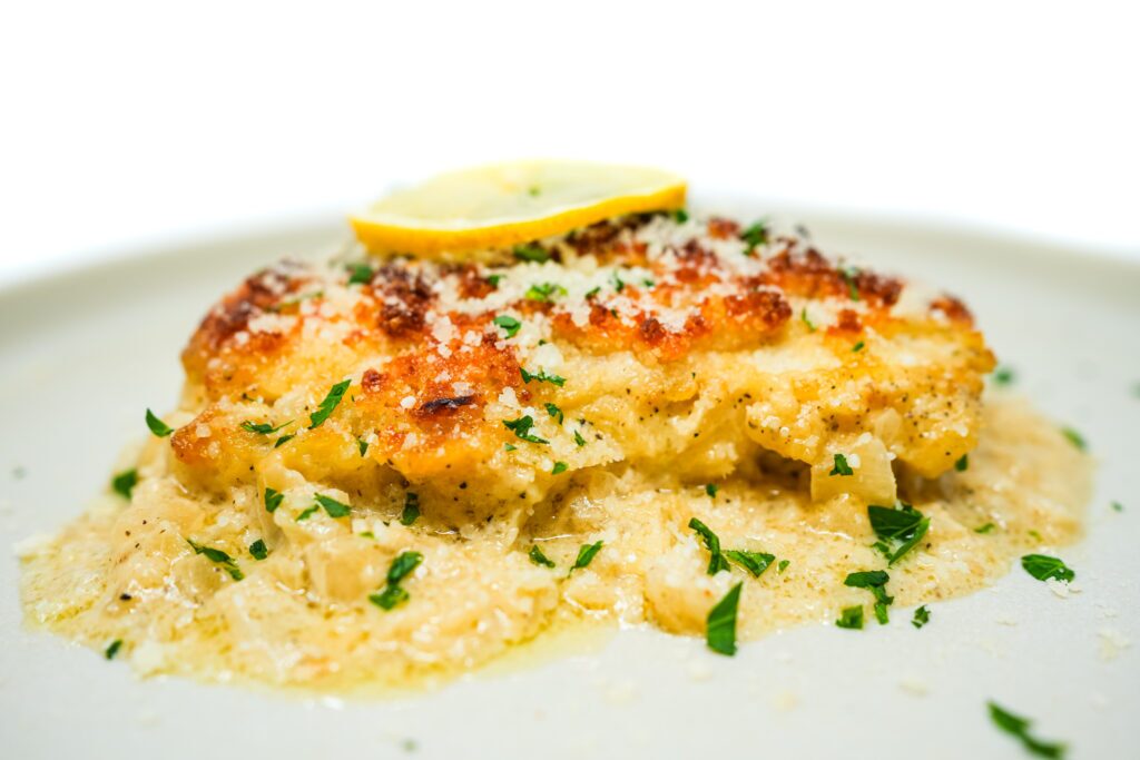 Plate of Cusk Au Gratin featuring tender cusk fish fillets topped with a creamy, cheesy sauce and a crispy, golden breadcrumb crust