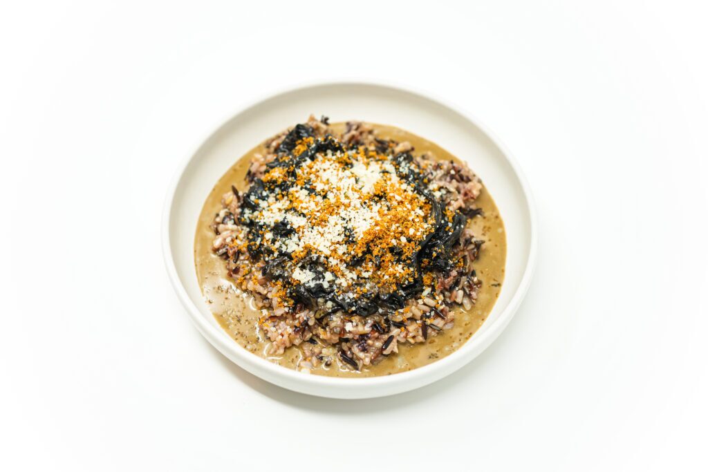A bowl of Black Trumpet Mushroom recipe with Cream Sauce served over wild rice, garnished with golden toasted breadcrumbs, fresh thyme, and grated Parmesan cheese.