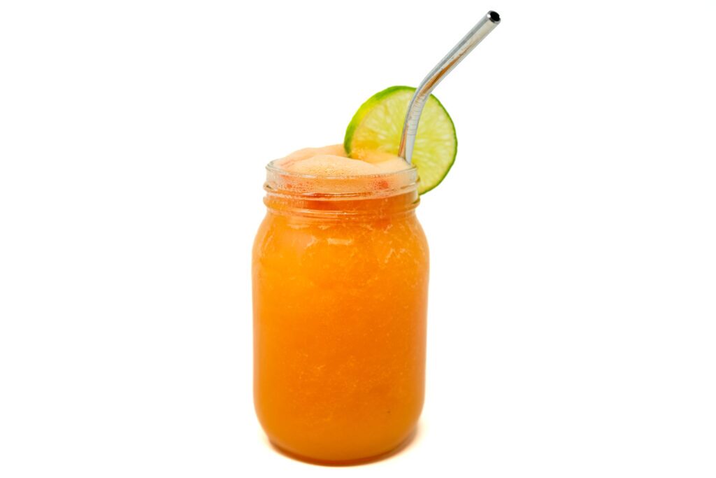 Papaya Punch drink served in a glass, featuring a tropical blend of fresh papaya and tequila with hints of lime and citrus, garnished with a slice of lime for a refreshing and vibrant cocktail.