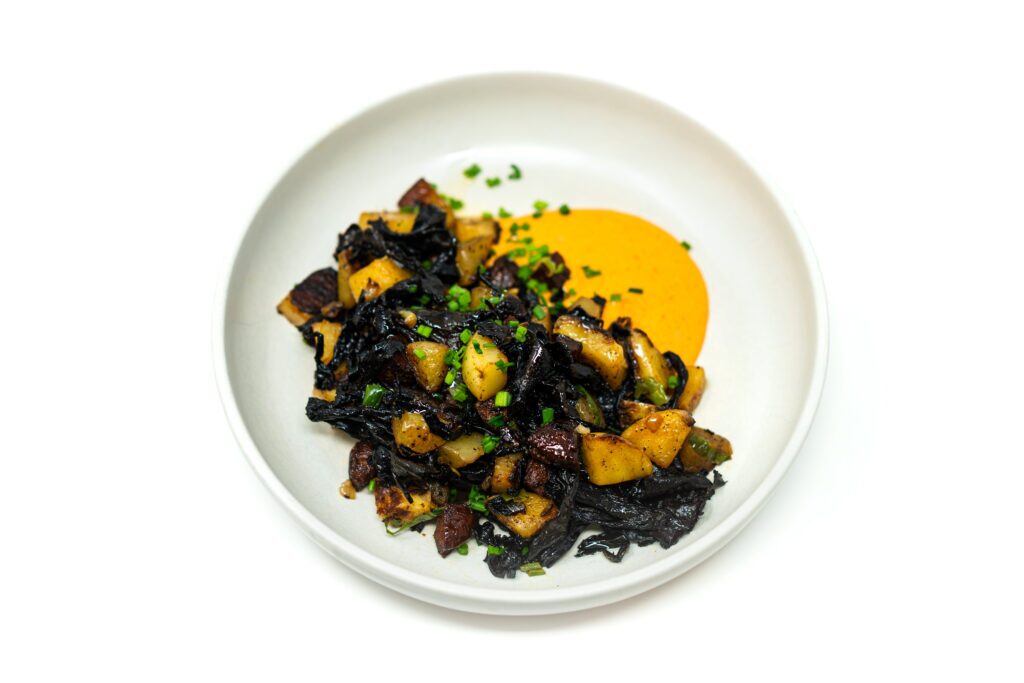 Crispy golden potatoes with seared wild mushrooms topped with a silky paprika aioli and fresh herbs on a rustic plate