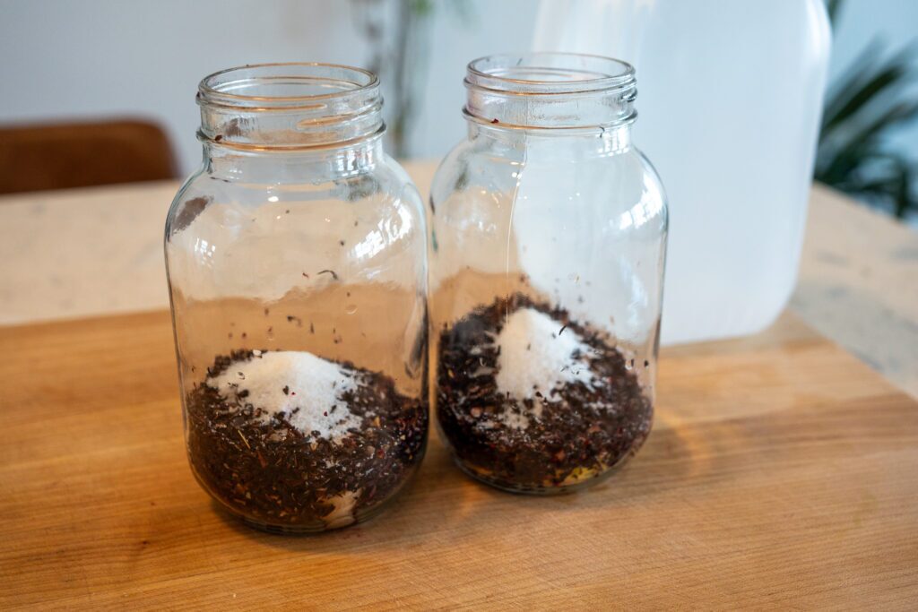 Dried hibiscus flowers, sugar, lemon zest and ginger in mason jars before adding water for cold brew tea
