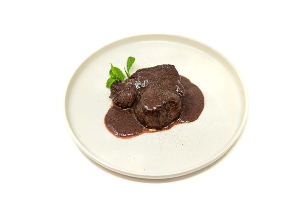 Seared center-cut tenderloin steak with a glossy red wine Dijon pan sauce on a white plate.
