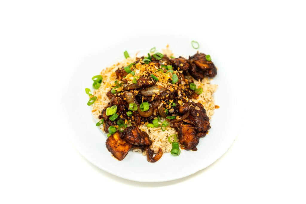 Overhead shot of Vietnamese BBQ chicken with charred pineapple coated in a dark palm sugar glaze, served over white rice with green onions.